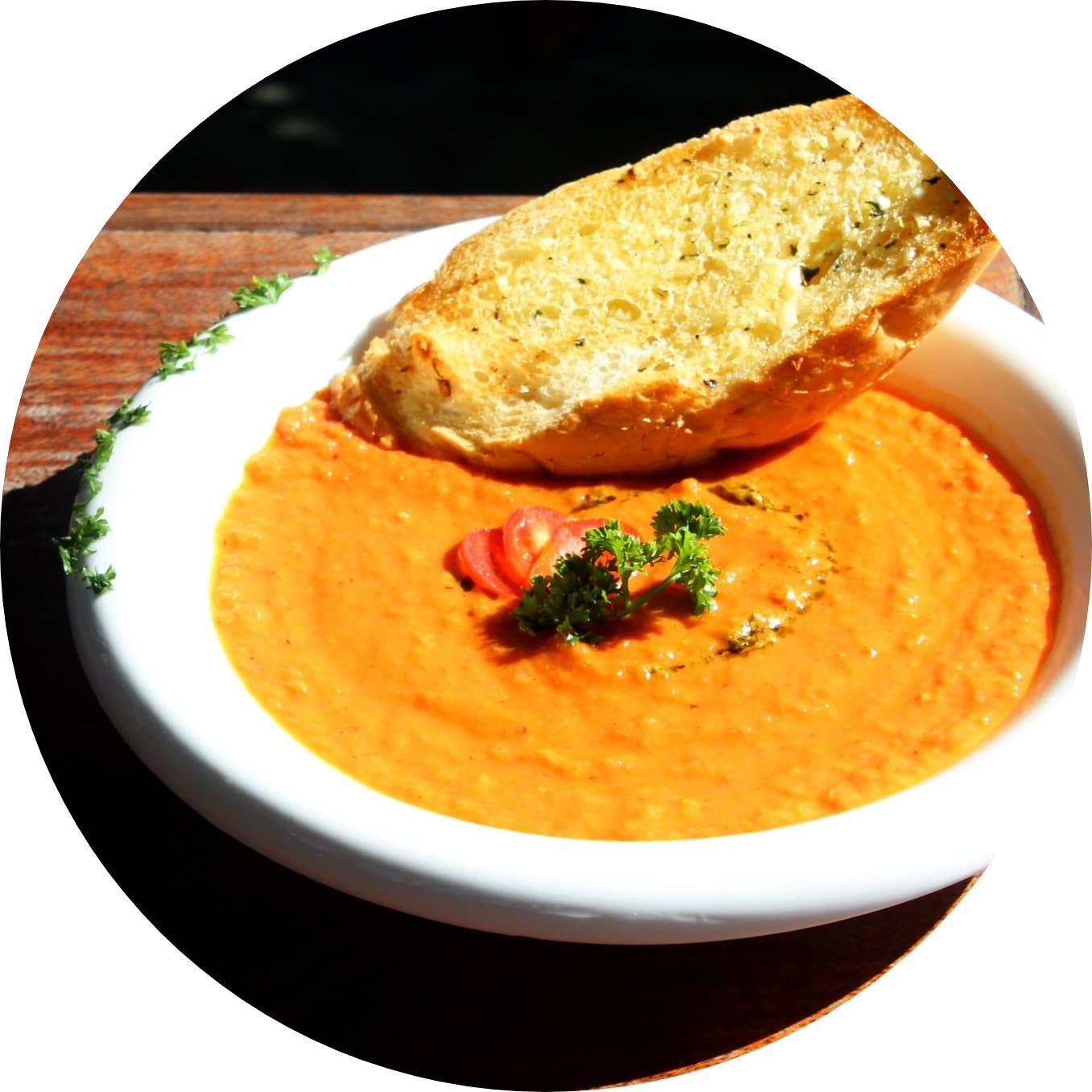 A white bowl filled with tomato soup and basil